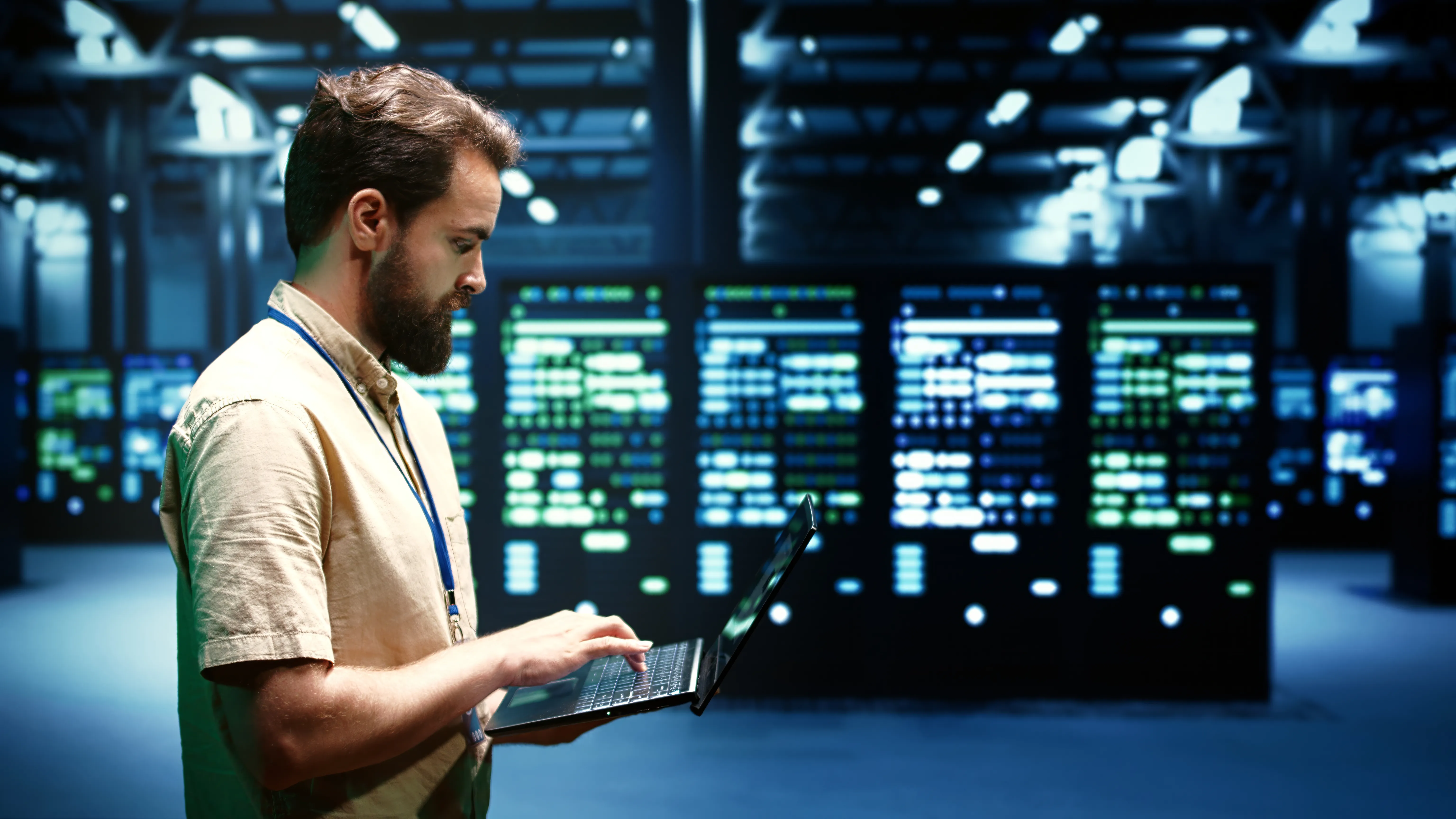 A man checks a laptop stood next to an array of servers.